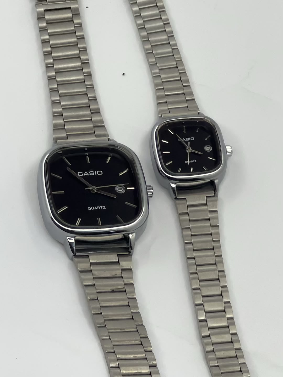 Silver square Casio watches with black dials and metal link bracelets
